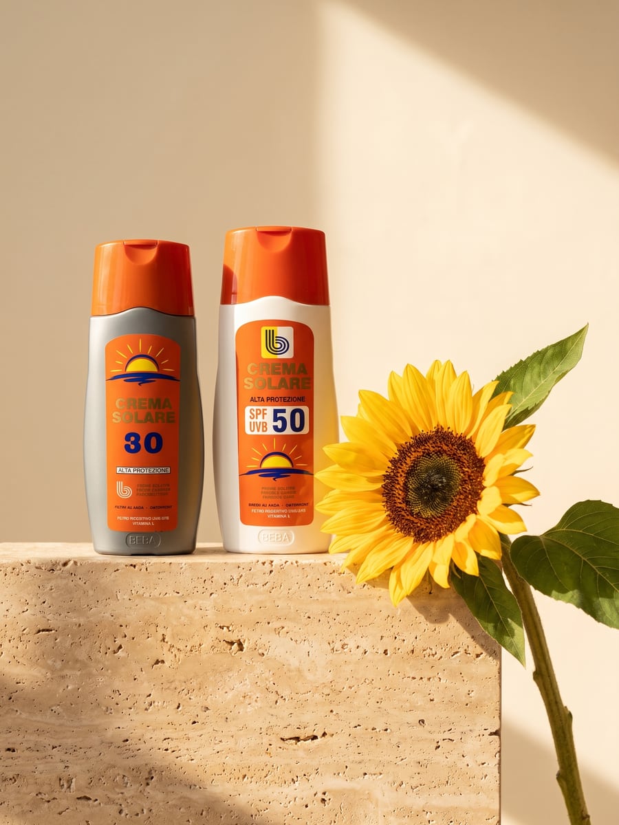 Kremra mbrojtës nga dielli SPF 30 dhe SPF 50 mbi travertinë, pranë një luledielli